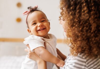 Happy,,Cheerful,African,American,Mother,Holds,A,Laughing,Baby,Daughter